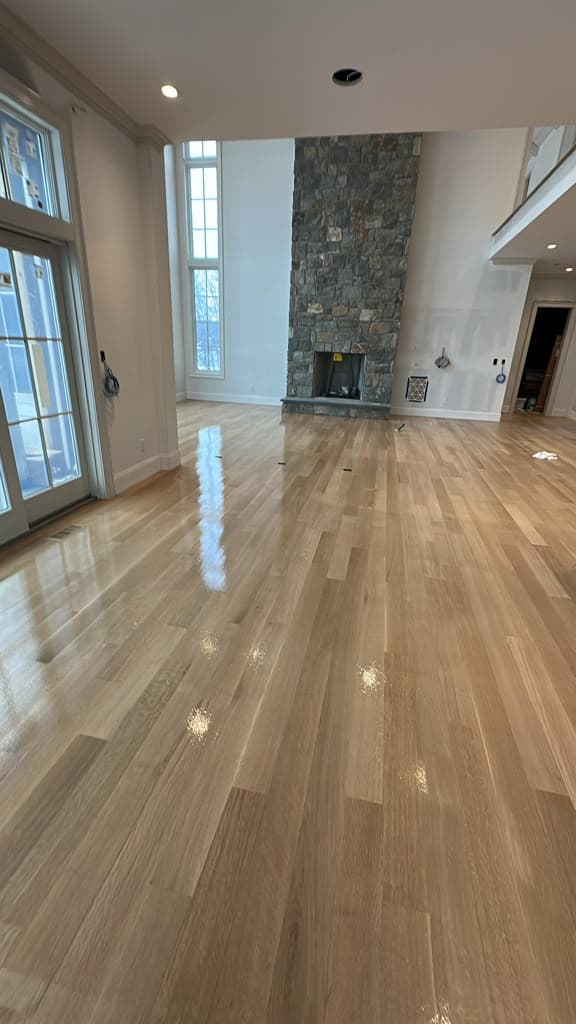 Refinished hardwood floor in a great room with a stone fireplace