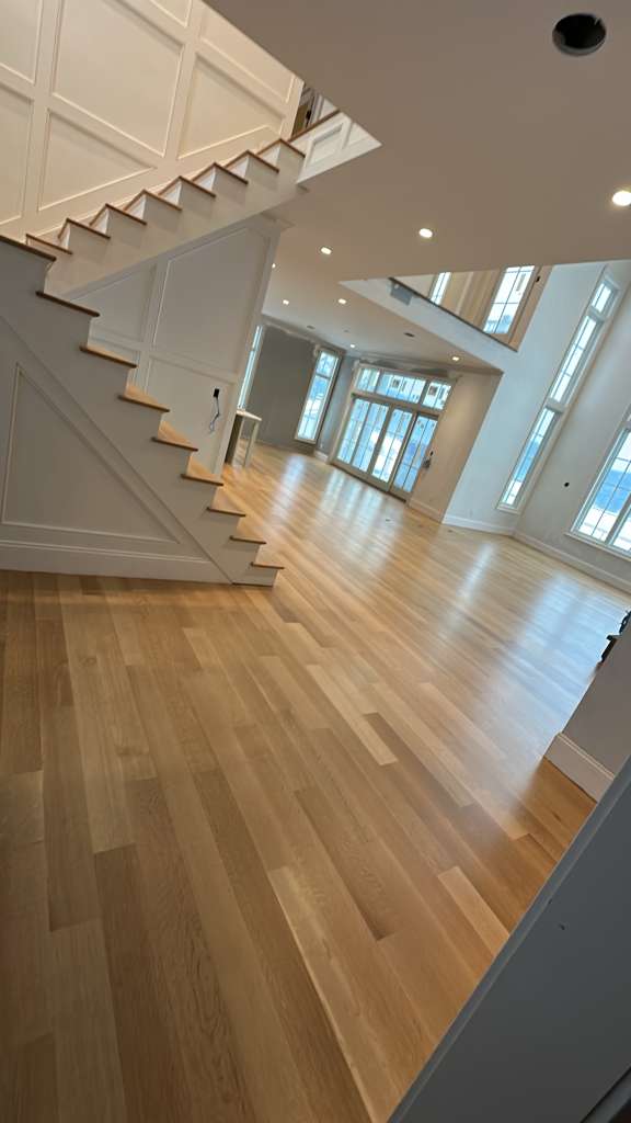 White oak hardwood floor installed in an open living area with a staircase